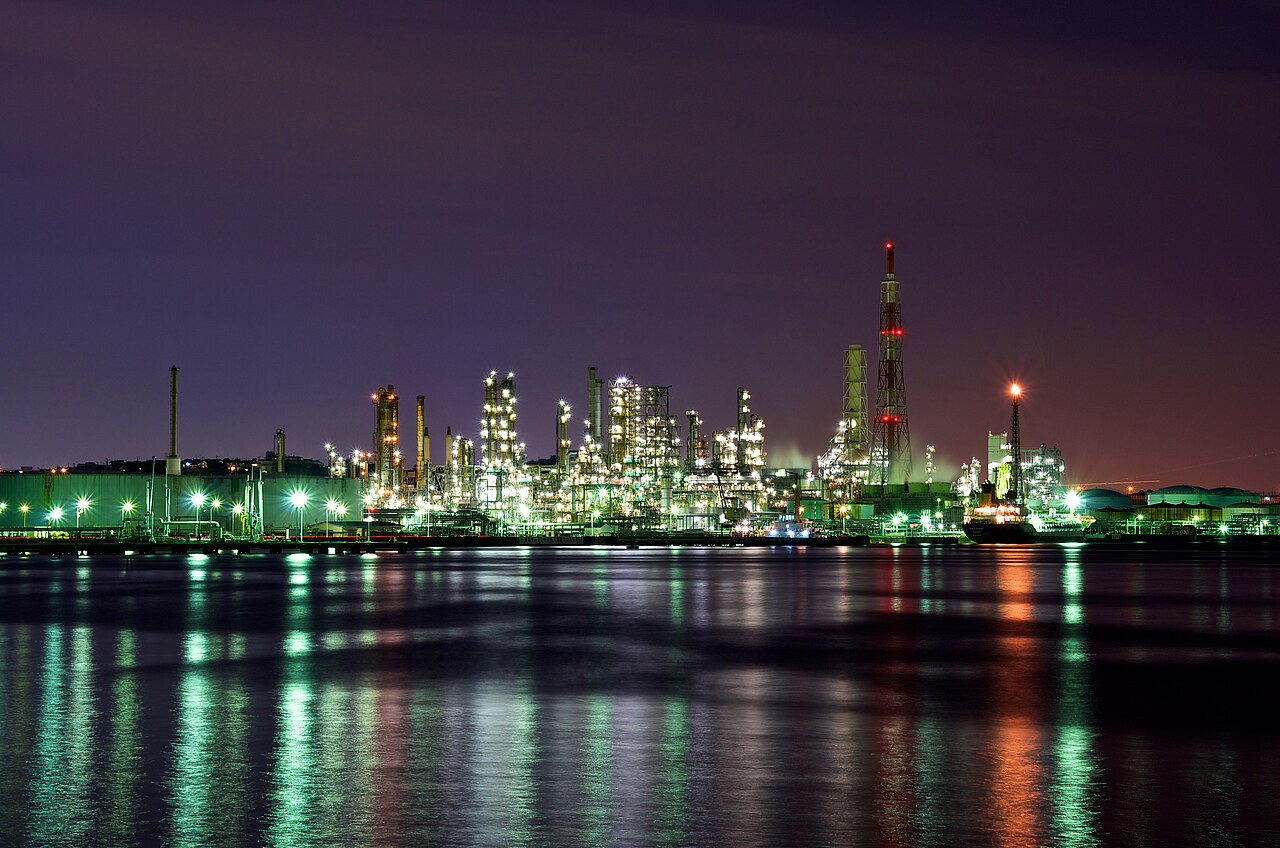 Oil refinery illuminated at night, symbol of the physical market behind crude oil options