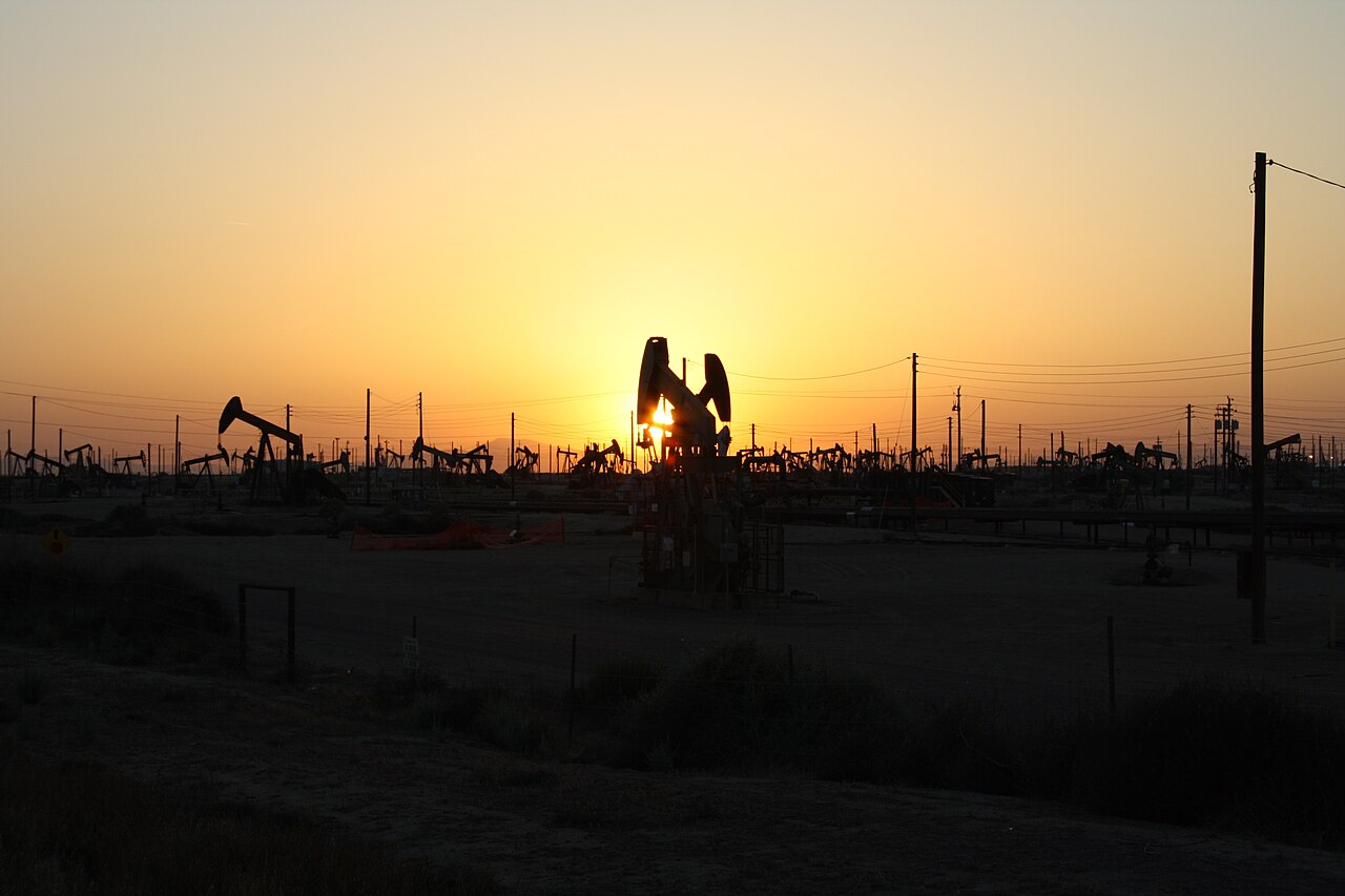 Pump jacks at sunset representing crude oil producers who hedge output with options collars